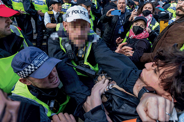 An overhead view of an outdoor altercation between a crowd of protesters and police officers. See long description.