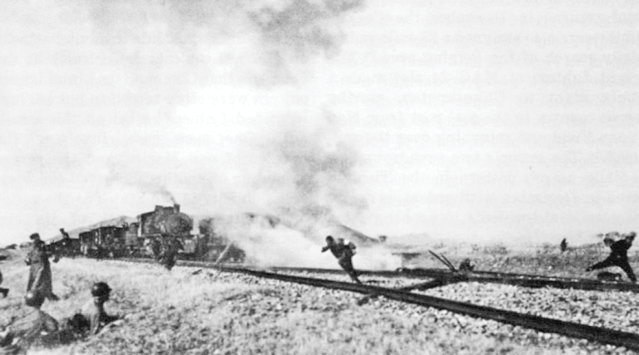 Two men are running in opposite directions away from a partially destroyed railway, with smoke rising from the tracks. A few U.S. soldiers are lying on the slope beneath the rails to take cover, while a train in the background comes to a stop.
