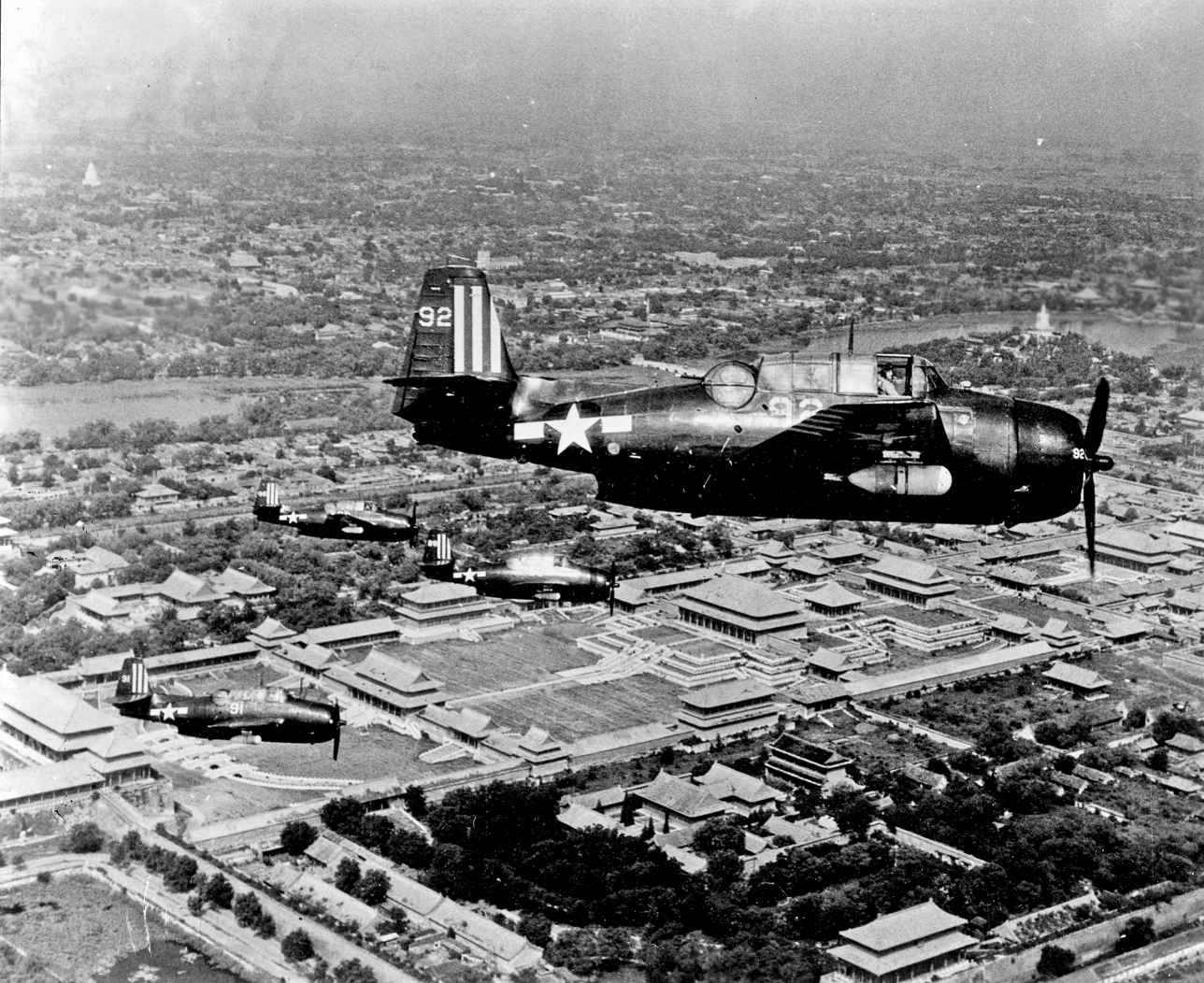 A U.S. T B M torpedo bomber flies over the Forbidden City in Beijing, with the crew members visible in their shared, three-man cockpit.