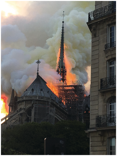 Photograph of the cathedral with the roof engulfed in flames and large billows of smoke.
