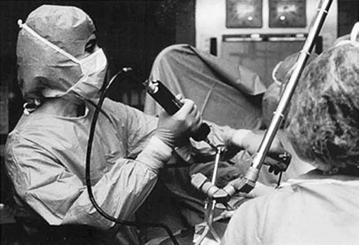 Two medical professionals, including Dr. Camran Nezhat, are in an operating room. Dr. Camran Nezhat is inserting a laparoscope into the patient’s abdomen.