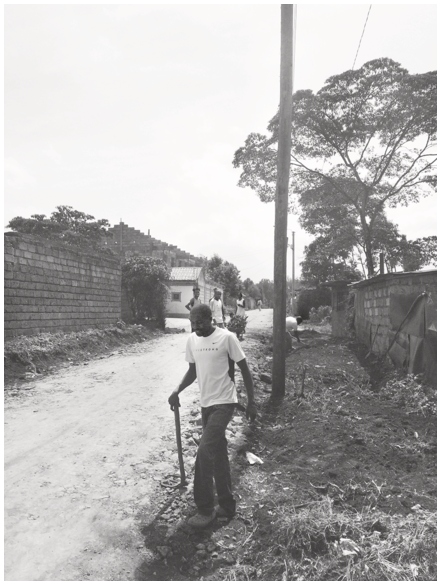 A photo of a labourer constructing a new stone road on the backstreets of the Ituura neighbourhood. See long description.