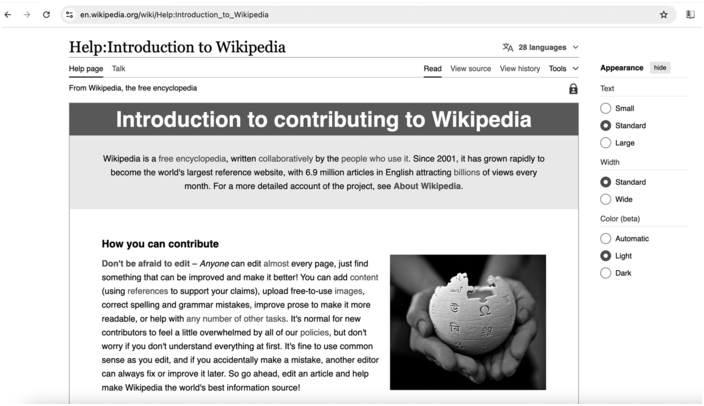 A screenshot of a help page titled, Introduction to Contributing to Wikipedia, has text accompanying a photo. The photo shows hands holding a partially assembled 3 D jigsaw puzzle of a globe, with pieces displaying letters from various languages.