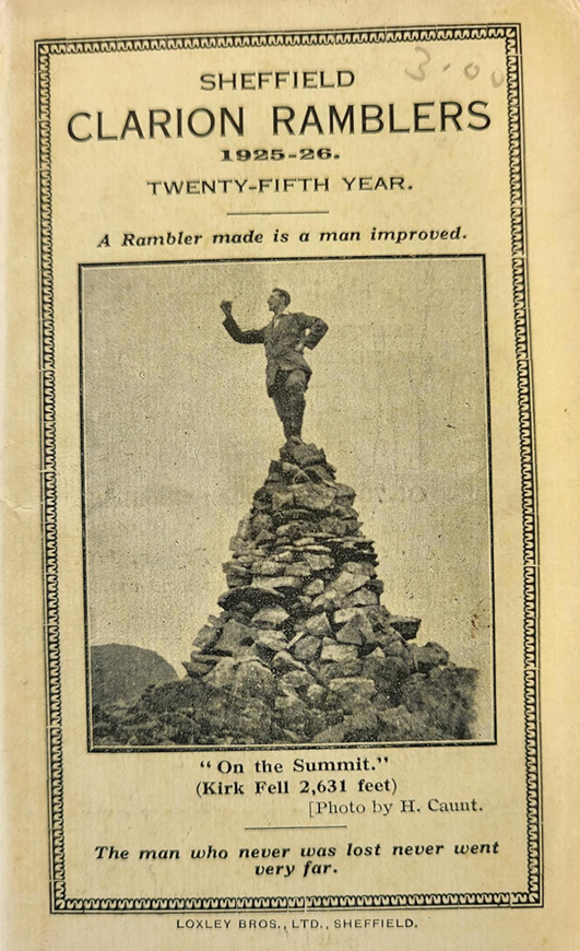 Cover of the Sheffield Clarion Ramblers Handbook 1925-26, featuring an inset balck and white photograph of a man standing atop a cairn with his fist held in the air. The tagline on the cover reads ‘A rambler made is a man improved’.