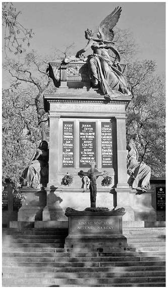 Wall-shaped monumental stele between two mourning figures displays a list of names under the motto: Even though they are dead, they still speak. This is surmounted by the statue of a winged goddess placing a palm branch on a coffin.