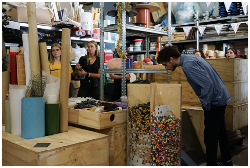 Community makerspace with recycled materials stored in wooden bins, promoting urban sustainability through creative reuse and resource sharing.