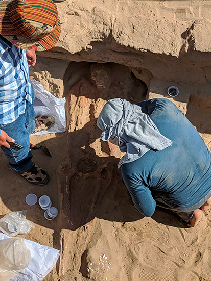 Nayo carefully exhuming a buried individual during archaeological fieldwork.