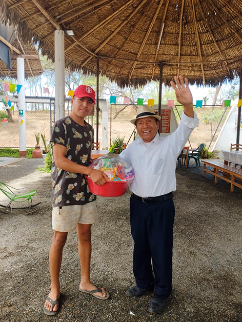 Professor Vidal Cobeñas receiving a food basket from Mateo, son of Maricela.