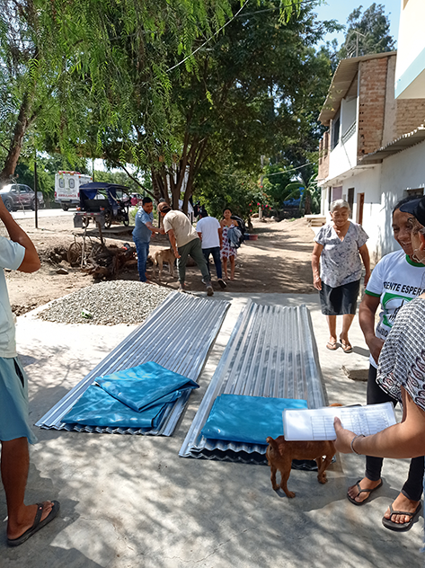Community members receiving metal sheets and plastic tarps in La Pintada for post-cyclone relief.