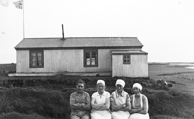 Four women sitting in front of a house.