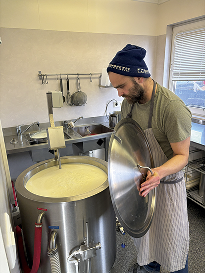 A man standing by a big pot making skyr.