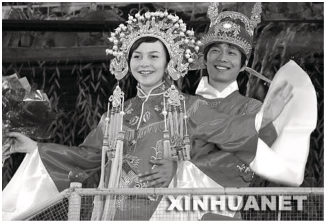 An image of a Russian woman and a Chinese man dressed in traditional Chinese wedding garments.