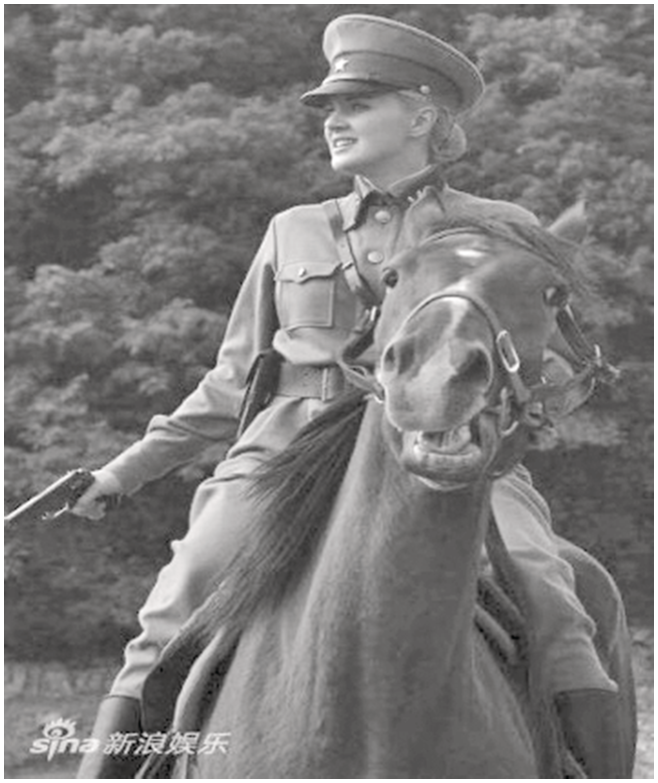 A female soldier in the Soviet uniform seated on a horseback and holding a gun in her right hand.