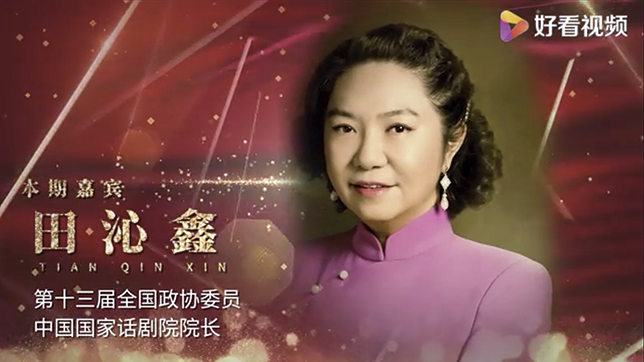 Tian Qinxin, President of the National Theatre of China, appears in a 2021 interview discussing the theatre’s responsibilities. She wears a pink qipao, traditional formal attire for women, and long drop earrings with teardrop-shaped pendants.