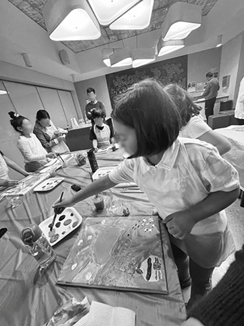 Mongolian children standing around the desks, drawing pictures.