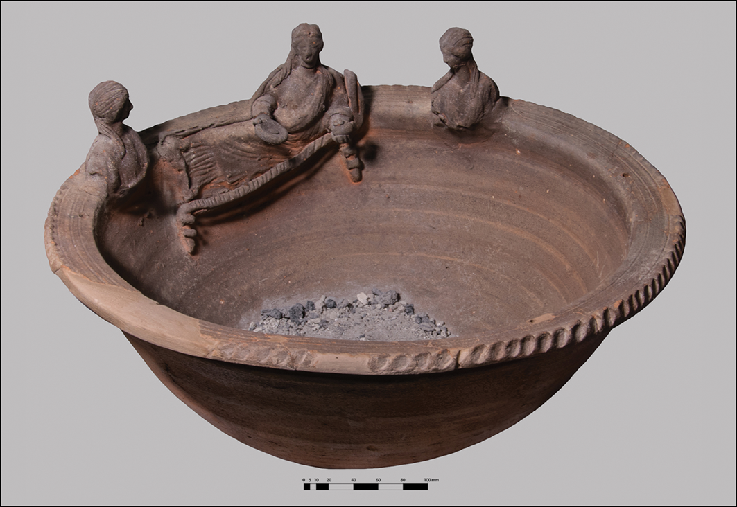 A terracotta censer with three human figures and a boat-like structure on its surface.