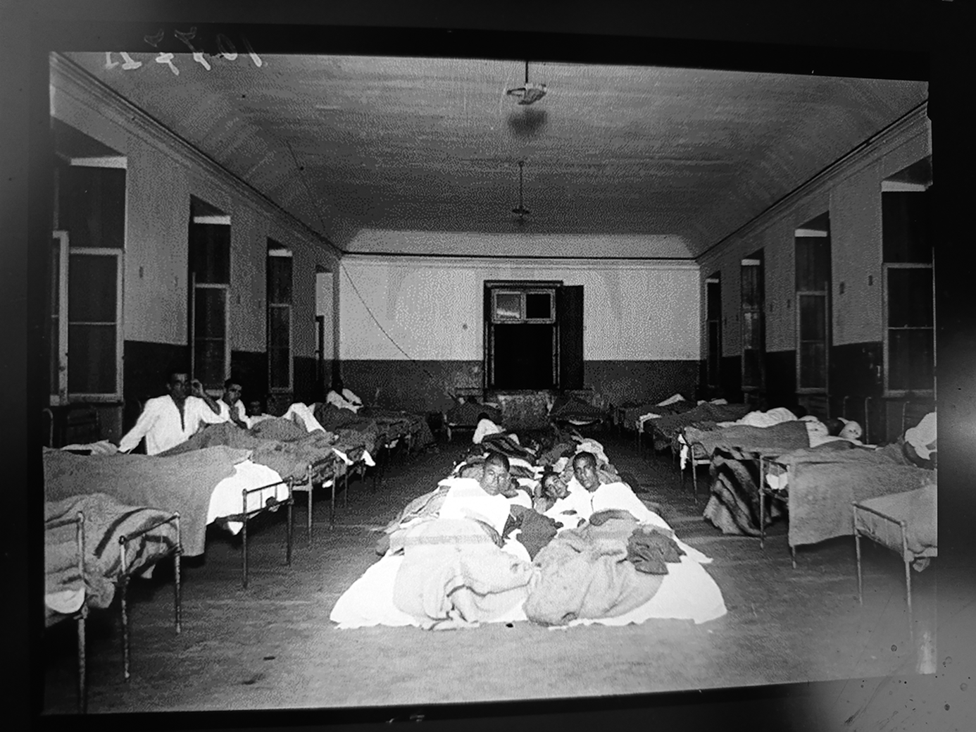 A dormitory for men in Miguel Bombarda hospital in 1926, showing several beds with patients lying on them.