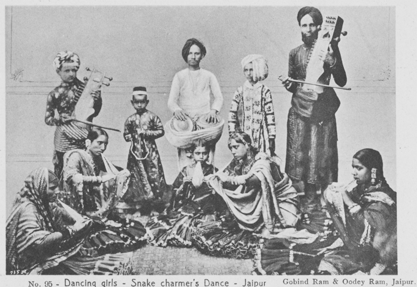 A vintage postcard featuring Nanhi Jan with an ensemble of nine performers, including five women and four men and boys, in a scene titled 'Dancing girls—Snake charmer’s Dance—Jaipur'.