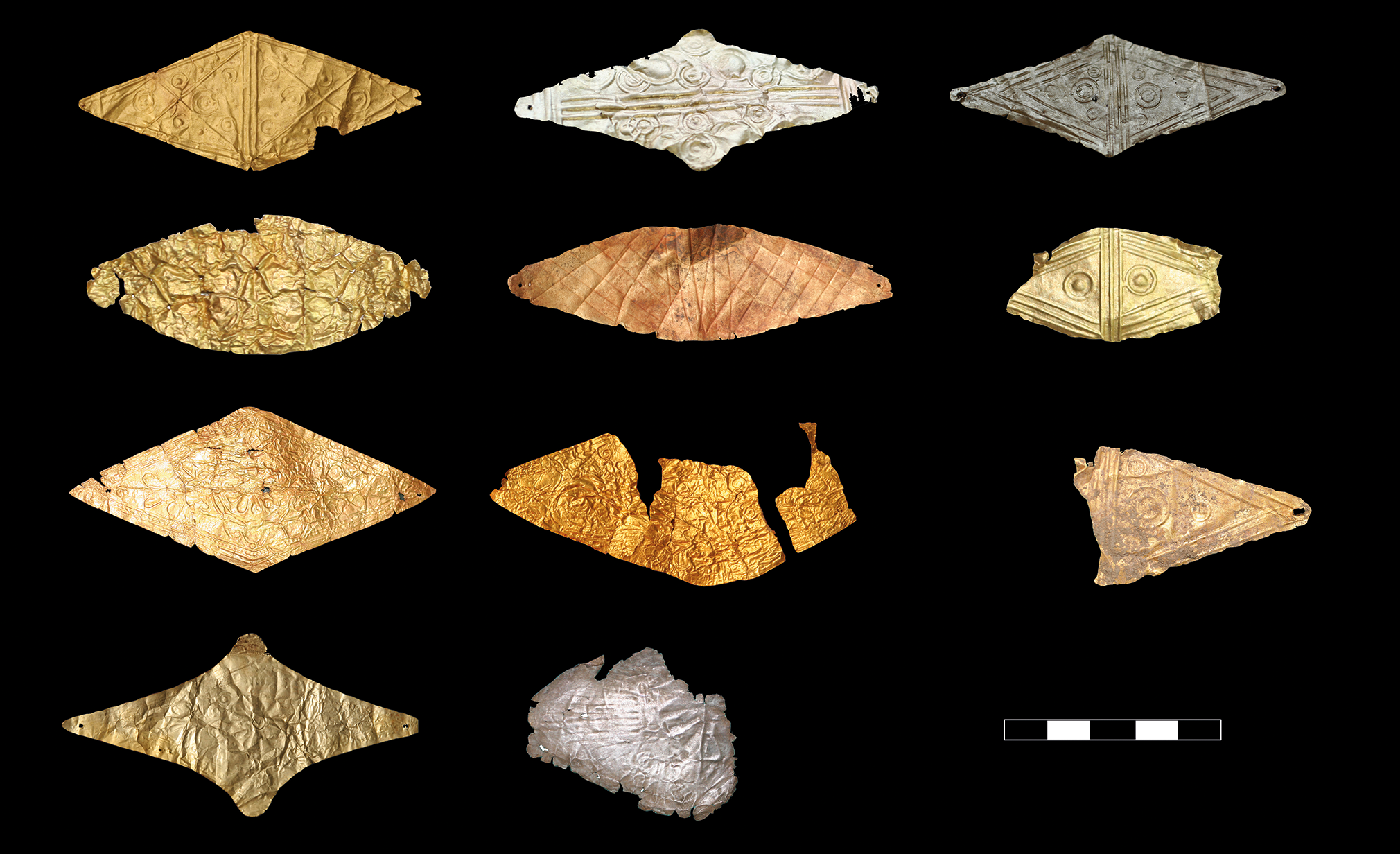 A collection of ancient mouthpieces, mostly gold with one silver example, arranged in rows against a black background.