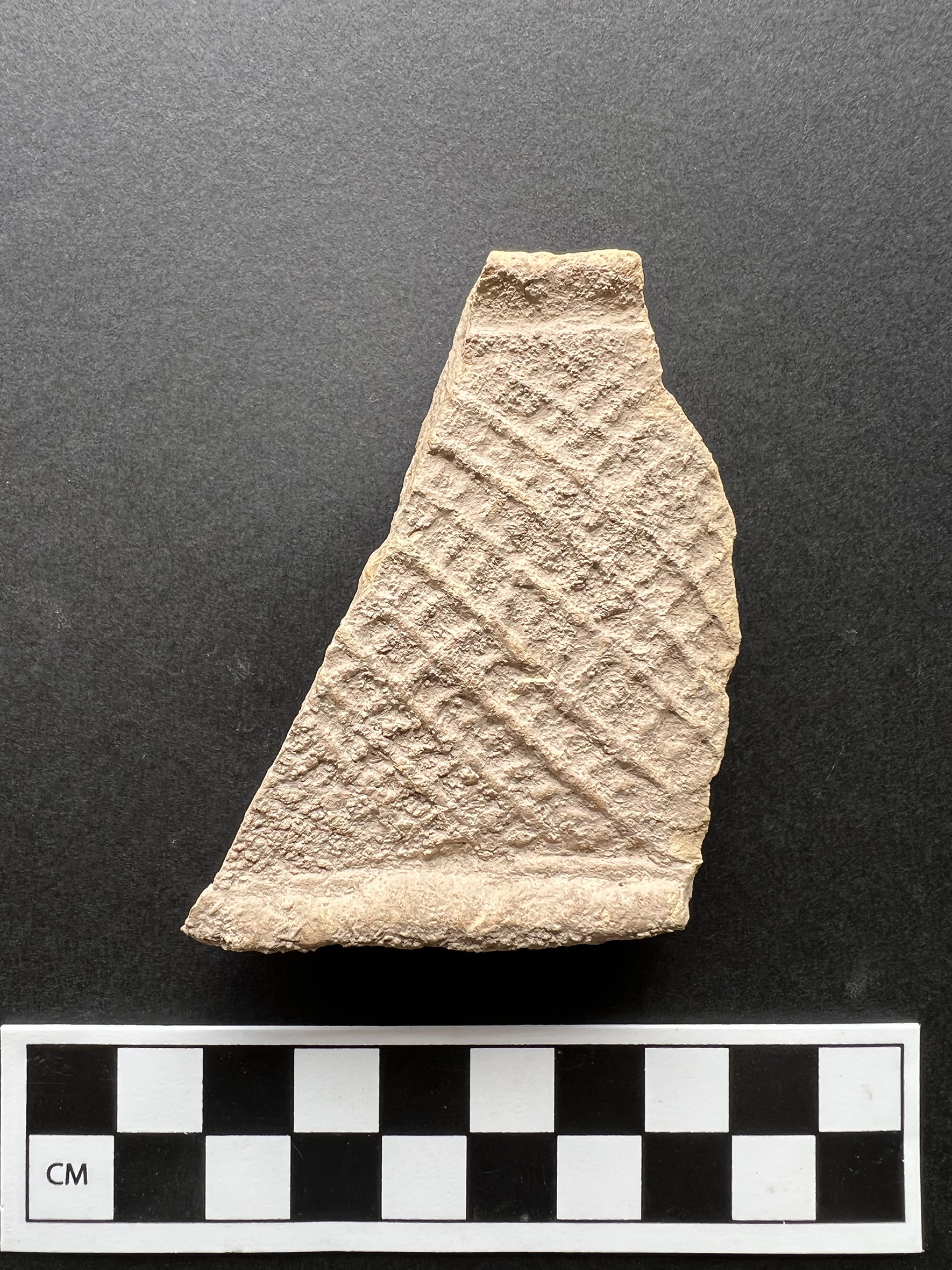 A terracotta bed model fragment on a black background with a measurement scale.