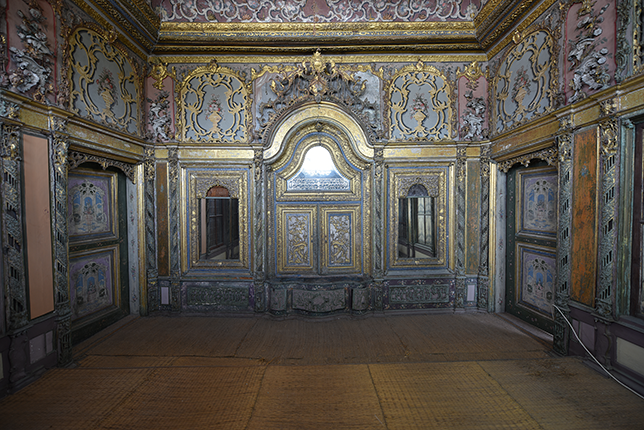 An interior view of Selim III’s lihye room. It captures the ornate mirrored wall with arched paneling, calligraphic medallions, and decorative molding before modern restoration.