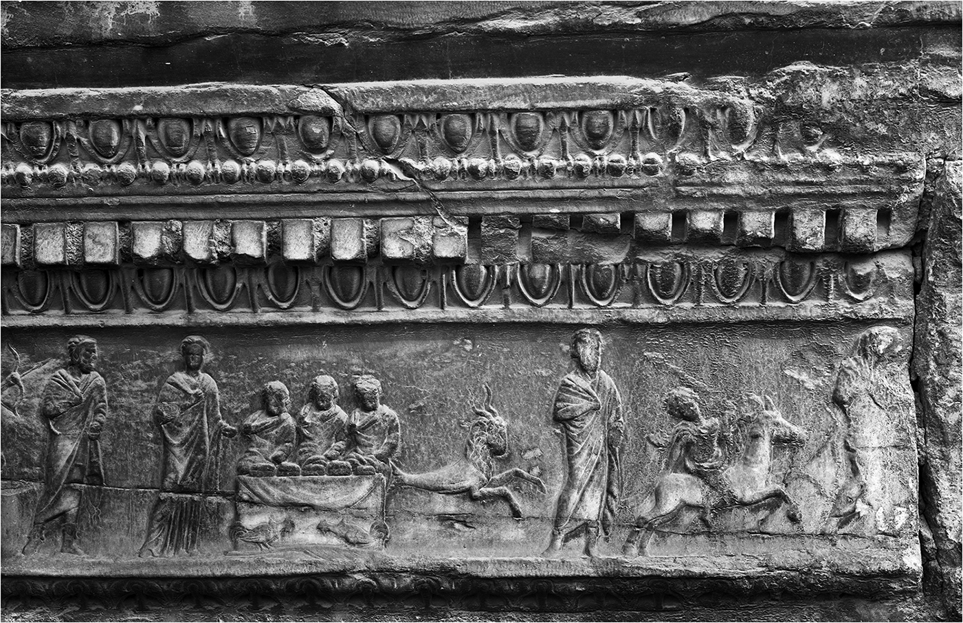 A relief sculpture depicting figures and animals in motion. See long description.