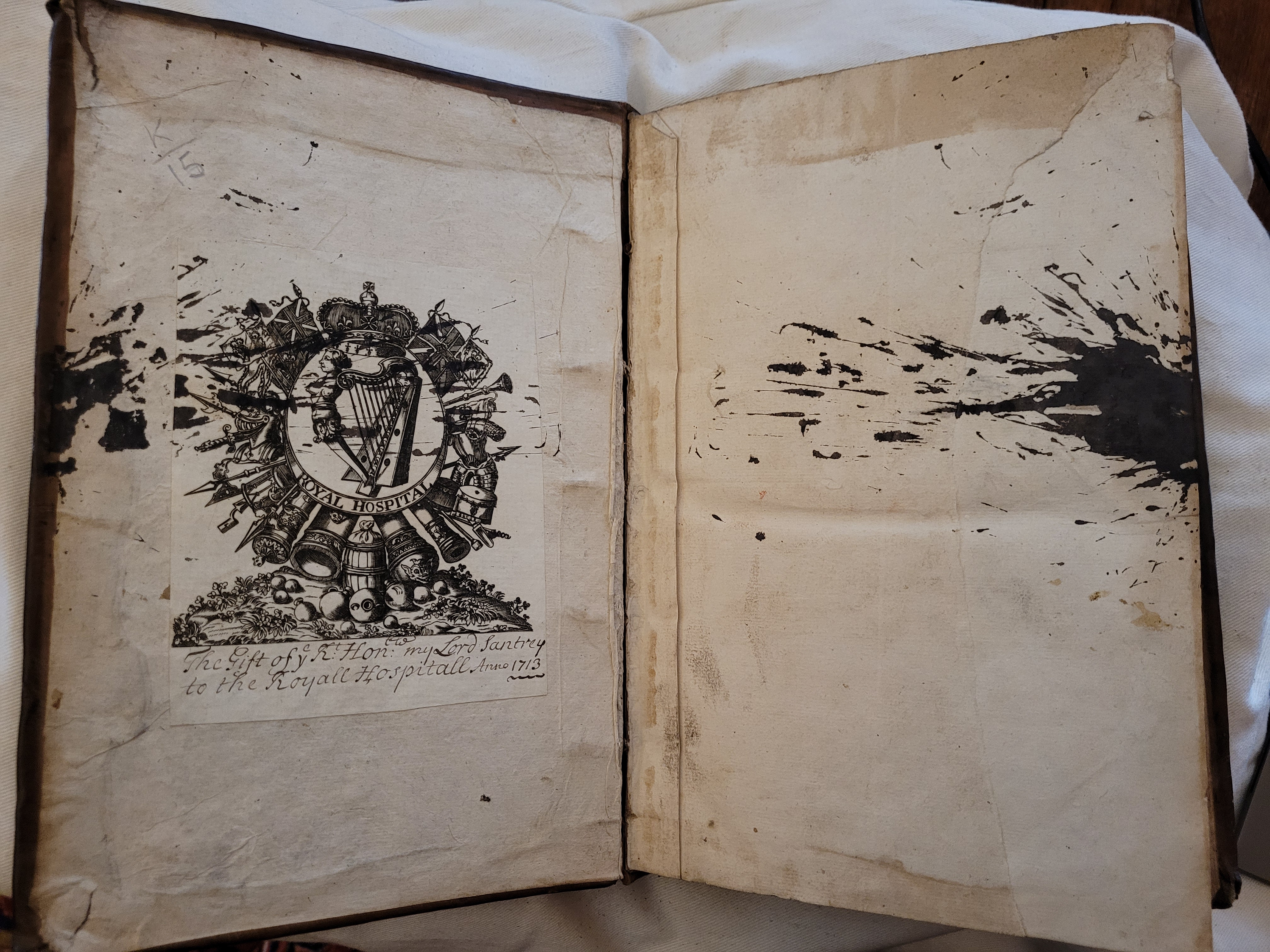 An open book with an ink-stained page featuring a crest and text.