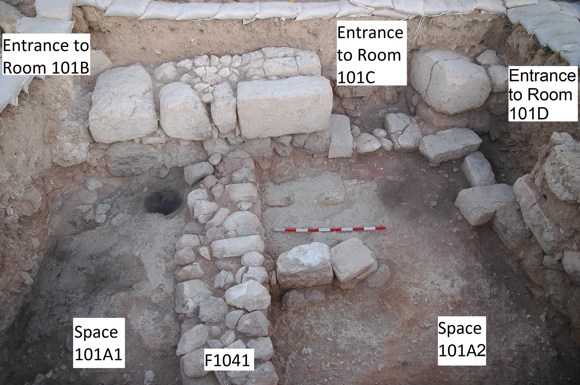 Excavated courtyard with entrances to rooms and a low partition wall.
