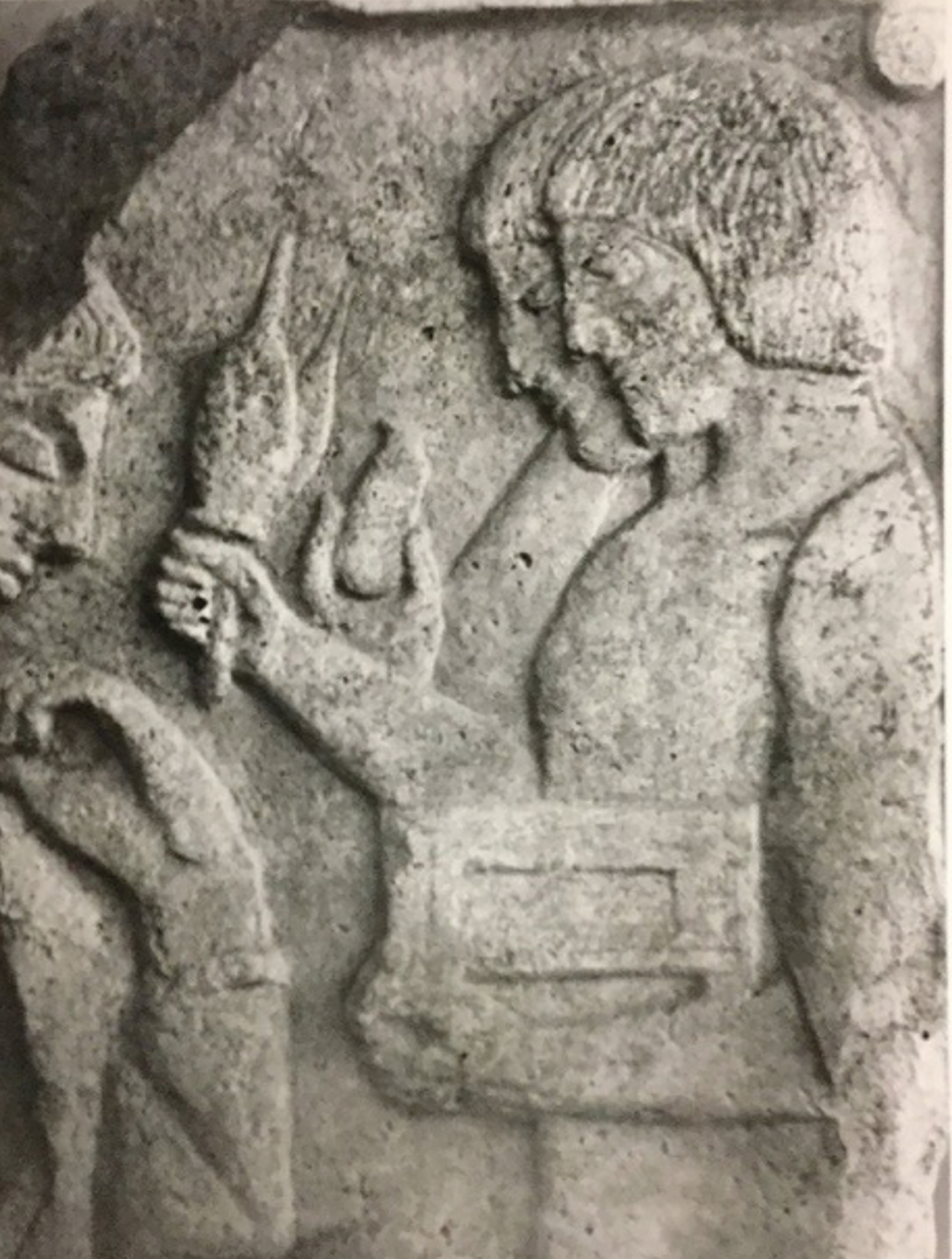 A stone relief carving depicting a person holding a small object.