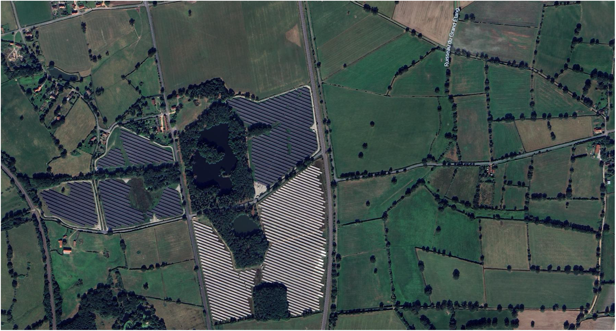 Satellite photo of a multi-use agricultural landscape featuring a large solar array integrated with forest patches and hedgerow-divided fields. See long description.